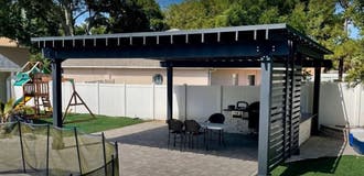 Black pergola with pavers and outdoor kitchen