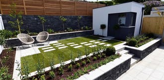 Stone pavers in grass with retaining wall gardens